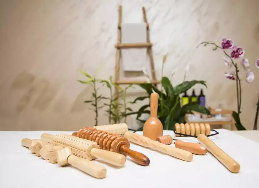 Nous voyons des instruments en bois pour pratiquer le madérothérapie qui est un massage utilisant des outils en bois. En arrière plan nous voyons de la végétation pour rendre l'image plus douce et plus qualitatif.