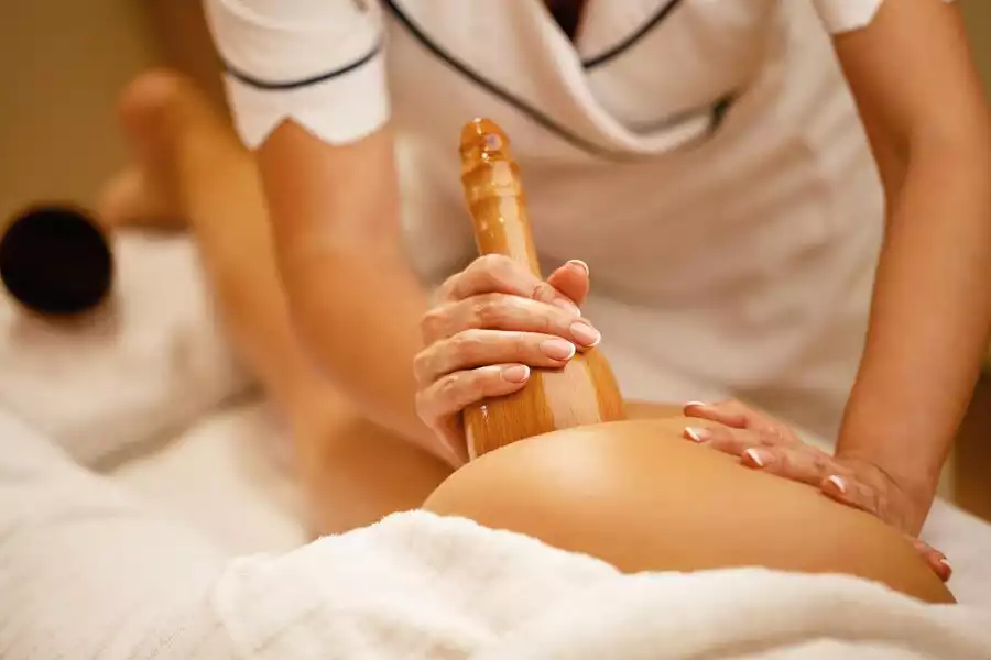 Une personne qui massage en pratiquant le madérothérapie qui est une technique de massage avec des outils en bois.