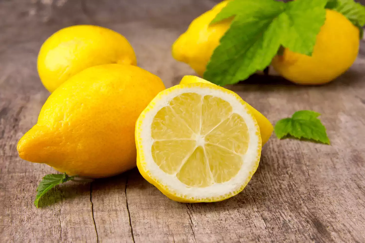 Sur cette image on voit des citrons sur une table en bois.