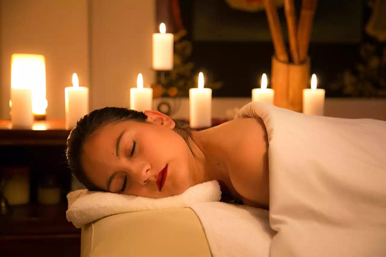 Une femme se fait masser dans une ambiance relaxante avec des bougie.